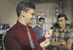Хьюбер со своими аспирантами Хаканом Олкаем и Виспутом (слева направо), с бутылочкой, содержащей катализаторы, используемые для создания зеленого топлива.